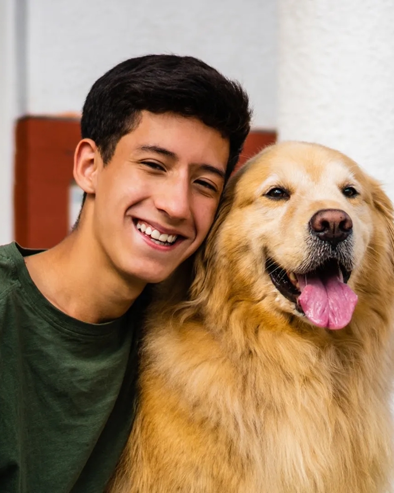 Student smiling while holding a golden retriever.