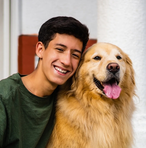Student smiling while holding a golden retriever.