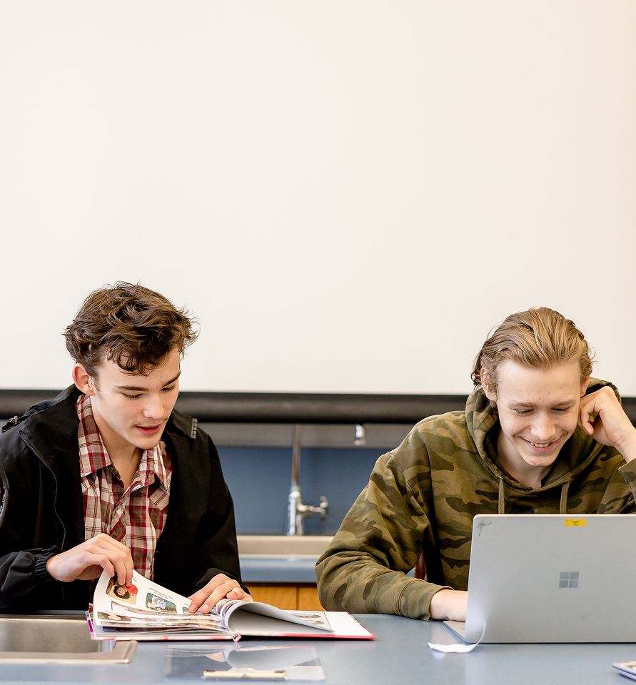Two students collaborating on a laptop in class.