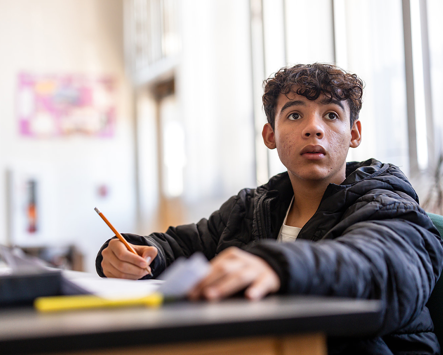 Student sitting at a desk with a pencil, focused during class at Hanna Academy.