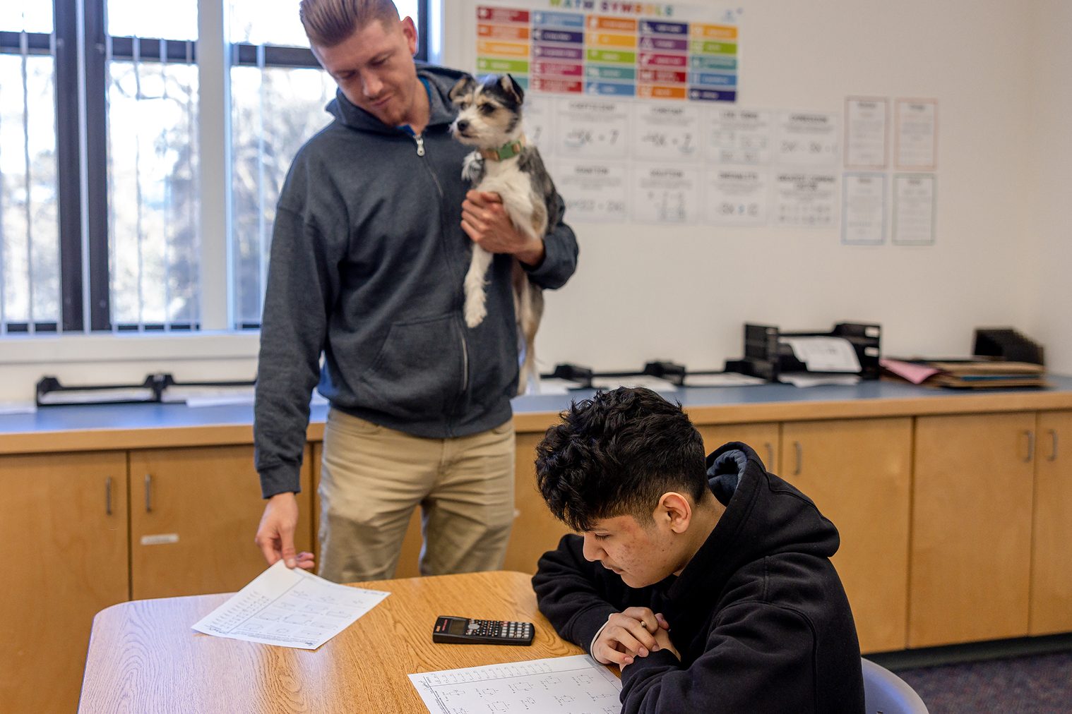 Teacher assisting student in classroom setting.