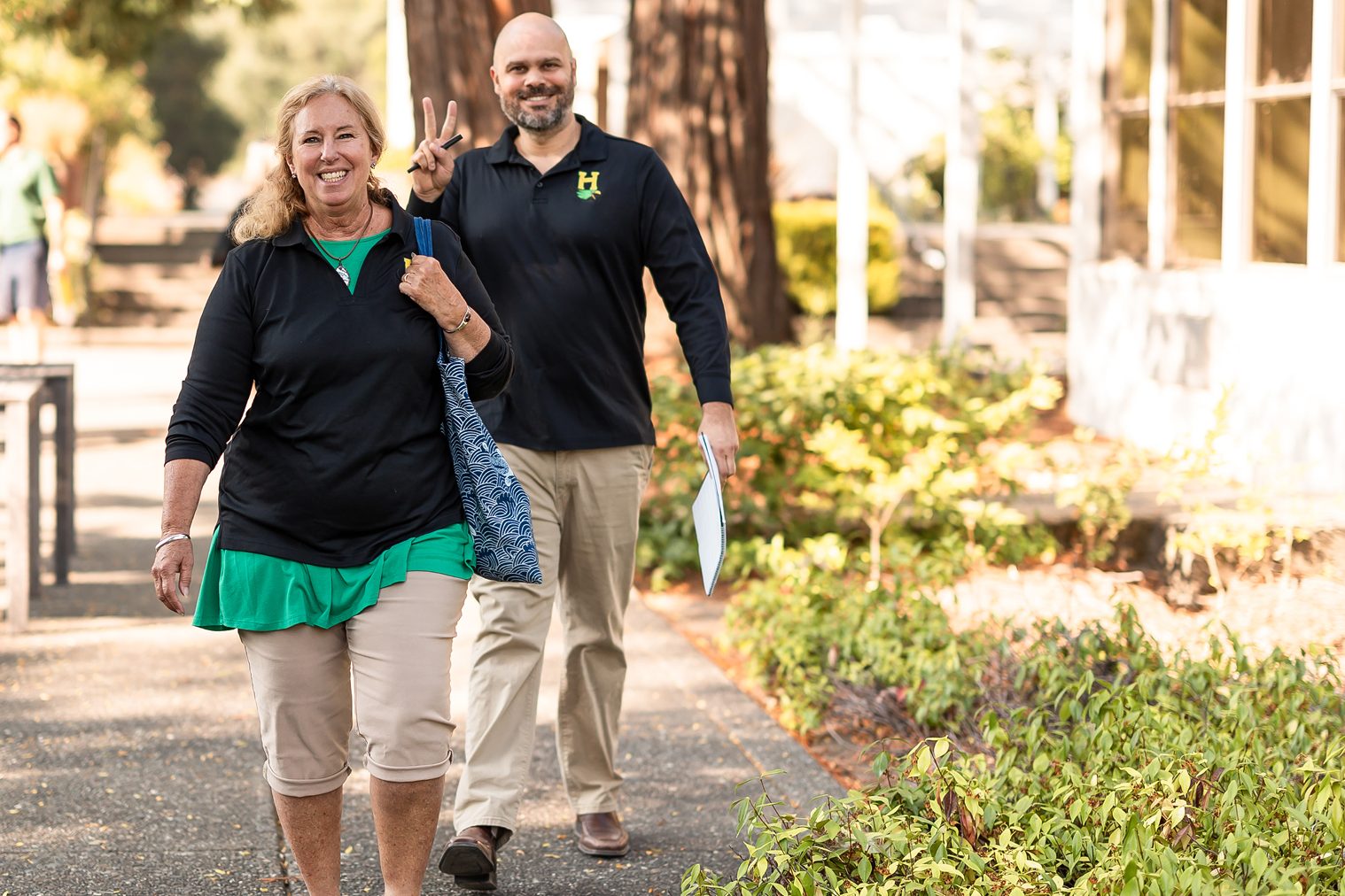 Teachers walking outdoors on wooded campus paths.