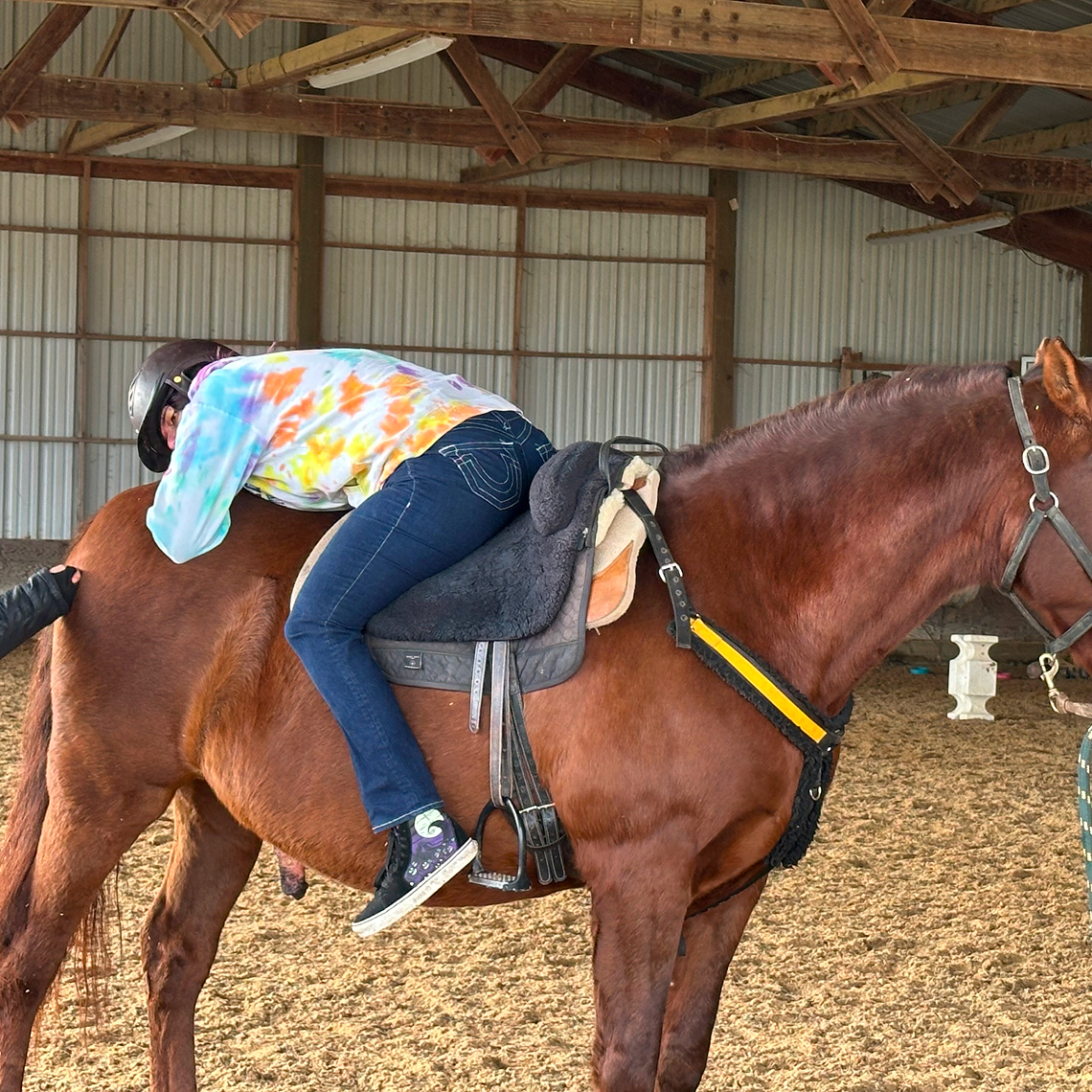 Student riding a horse during equestrian activity.