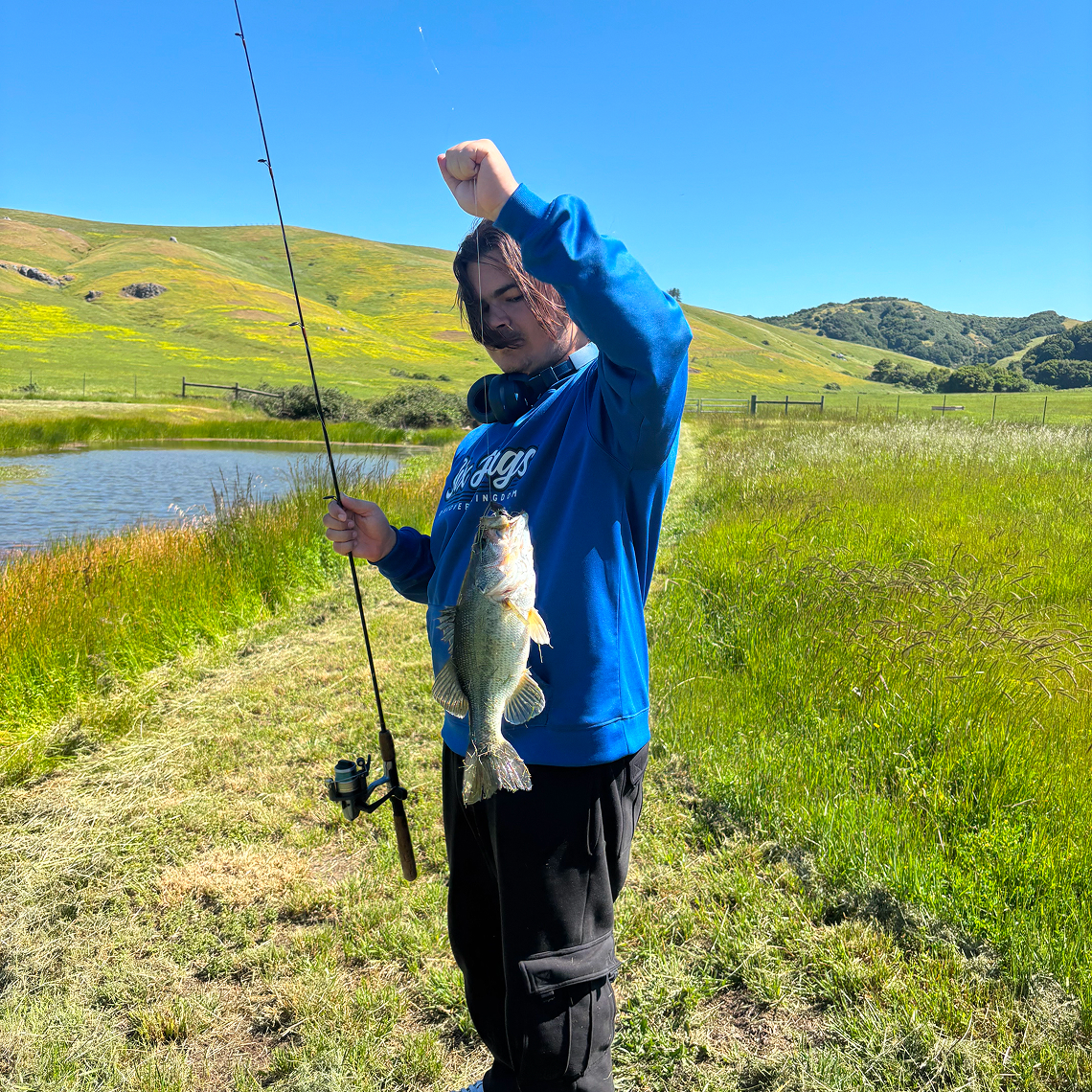 Student fishing on a grassy hillside.