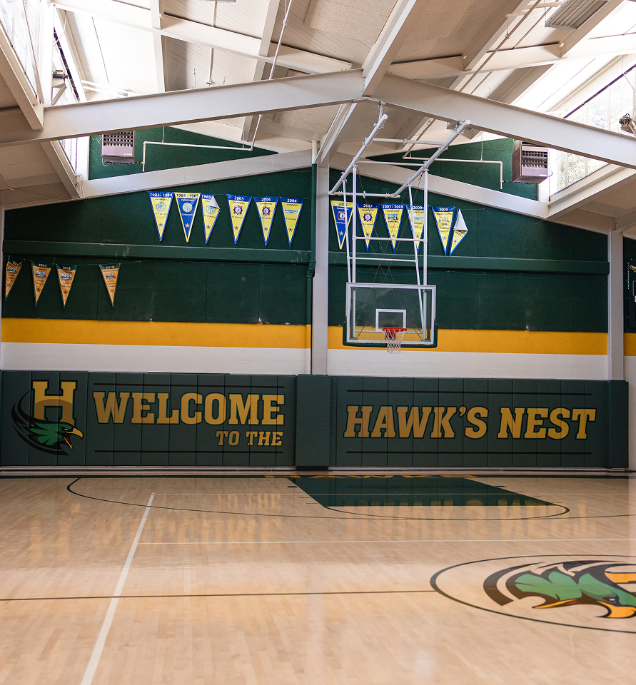 Gymnasium interior with basketball court and Hawk’s Nest welcome.