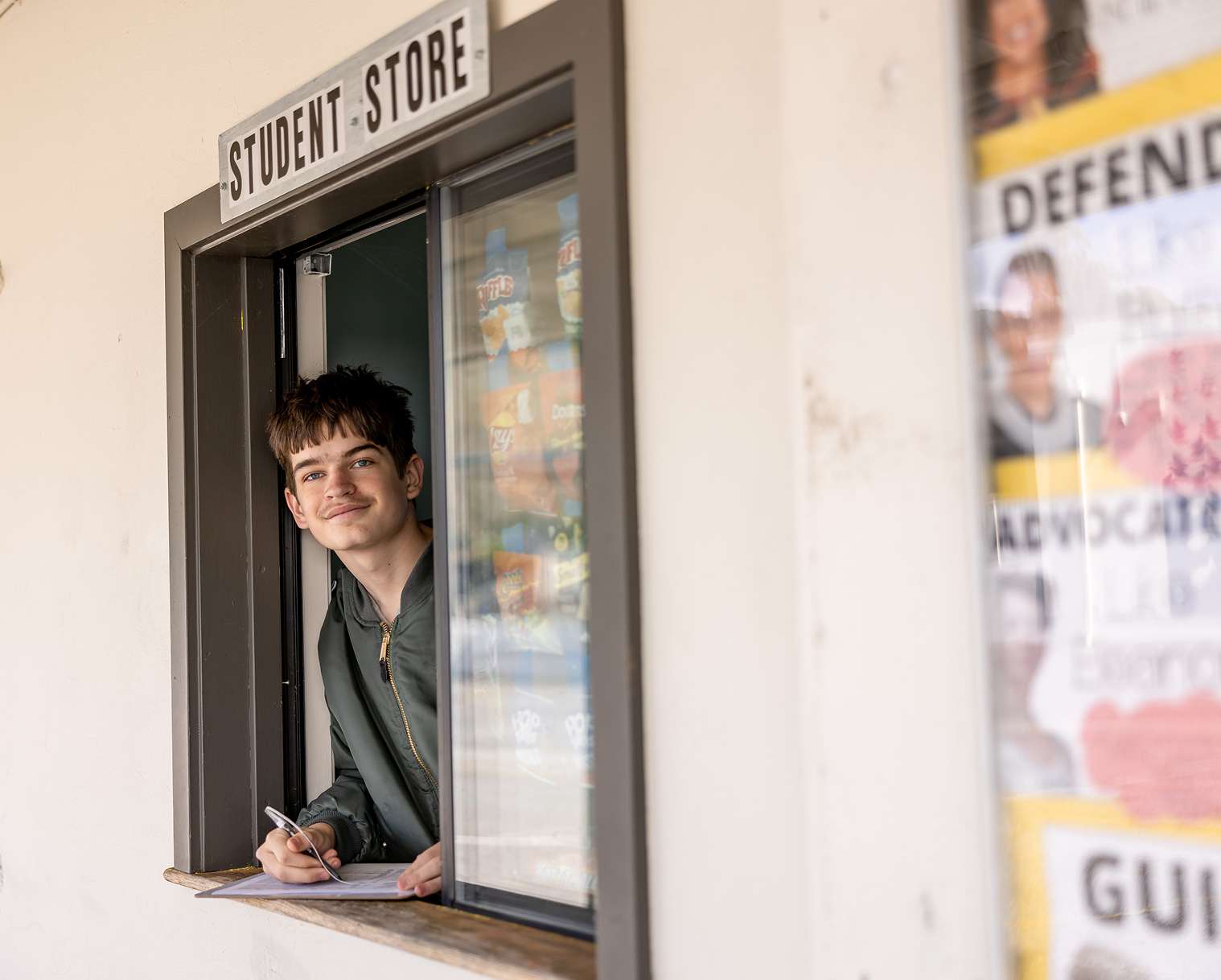 Student serving at the student store window on campus.