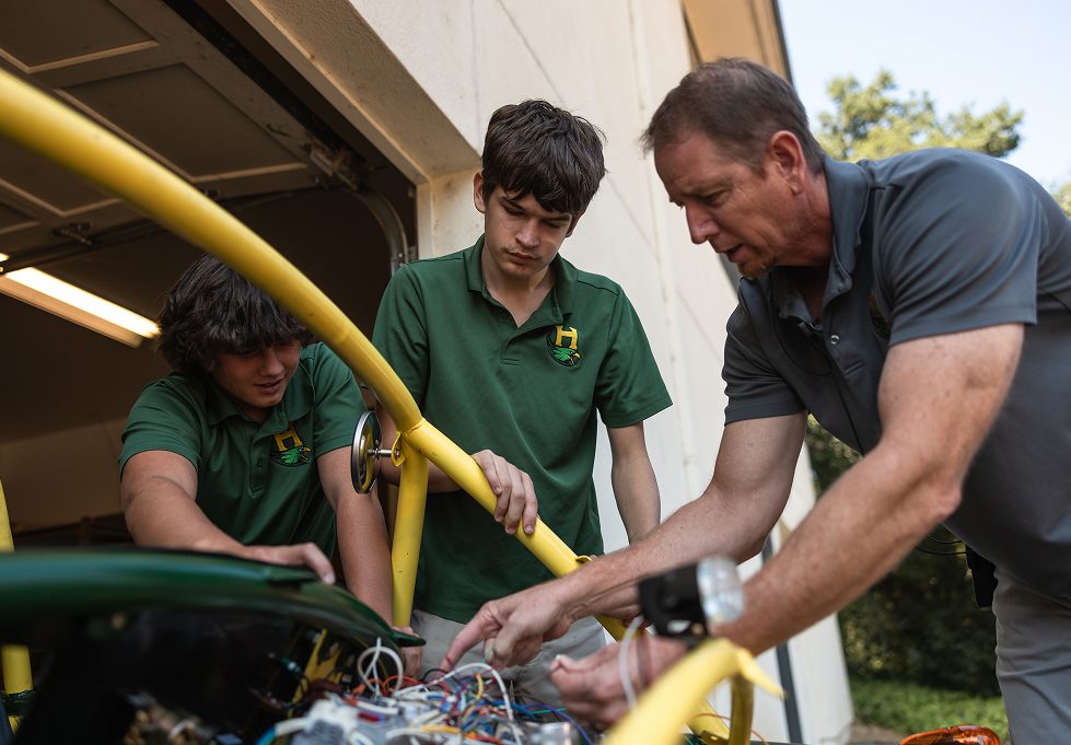 Instructor and students working together on a mechanical project in the workshop