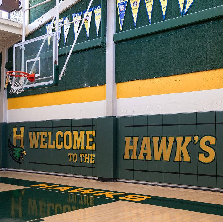 Hanna Academy gymnasium with basketball court and Hawks welcome sign